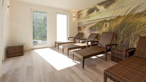A sunlit room with wicker furniture, large windows, and a beach mural. - Residence Waldidyll FeWo Lieblingsplatz - modern vacation apartment in a quiet location (Sellin)