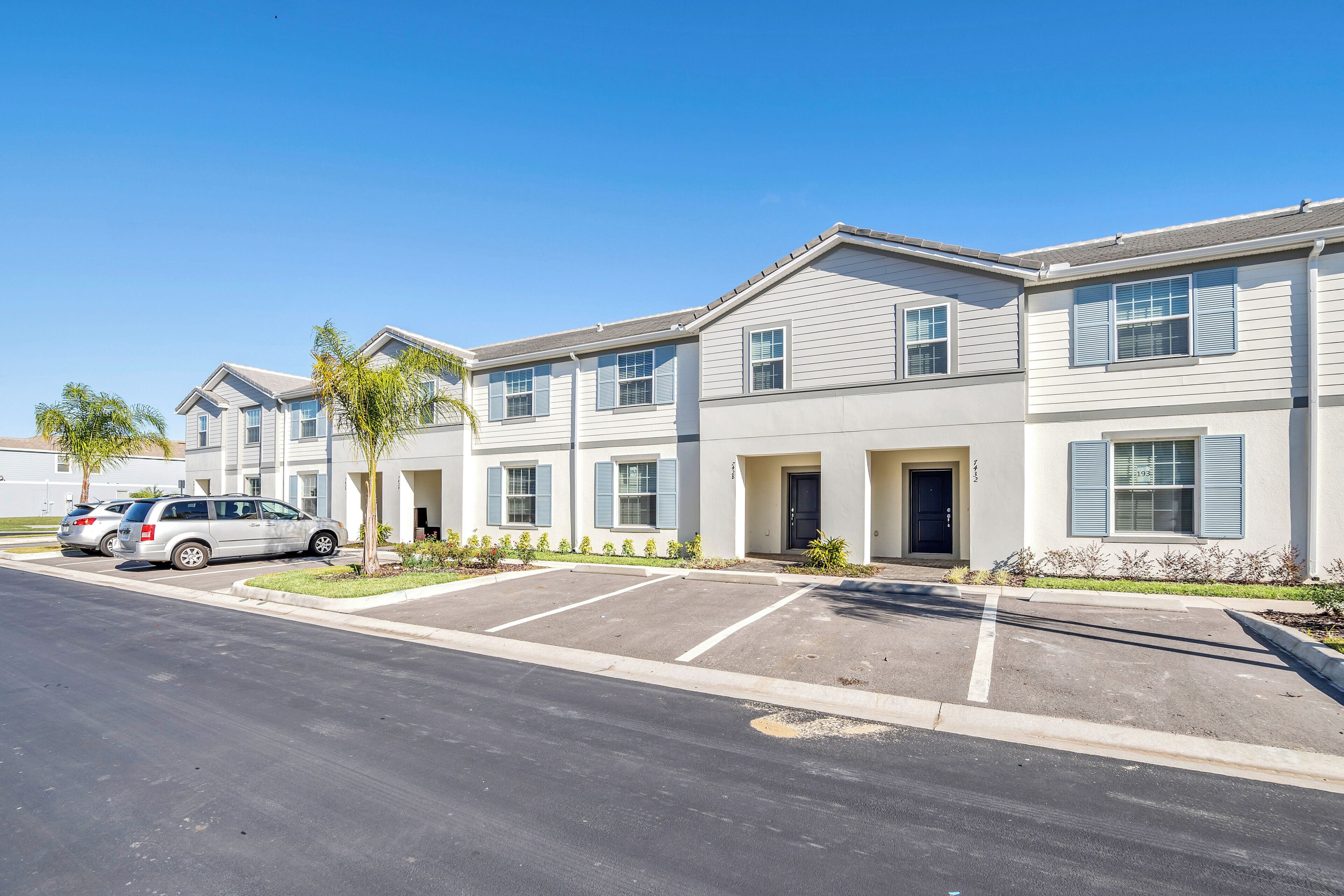A multi-story residential building with parking spaces and a clear sky.