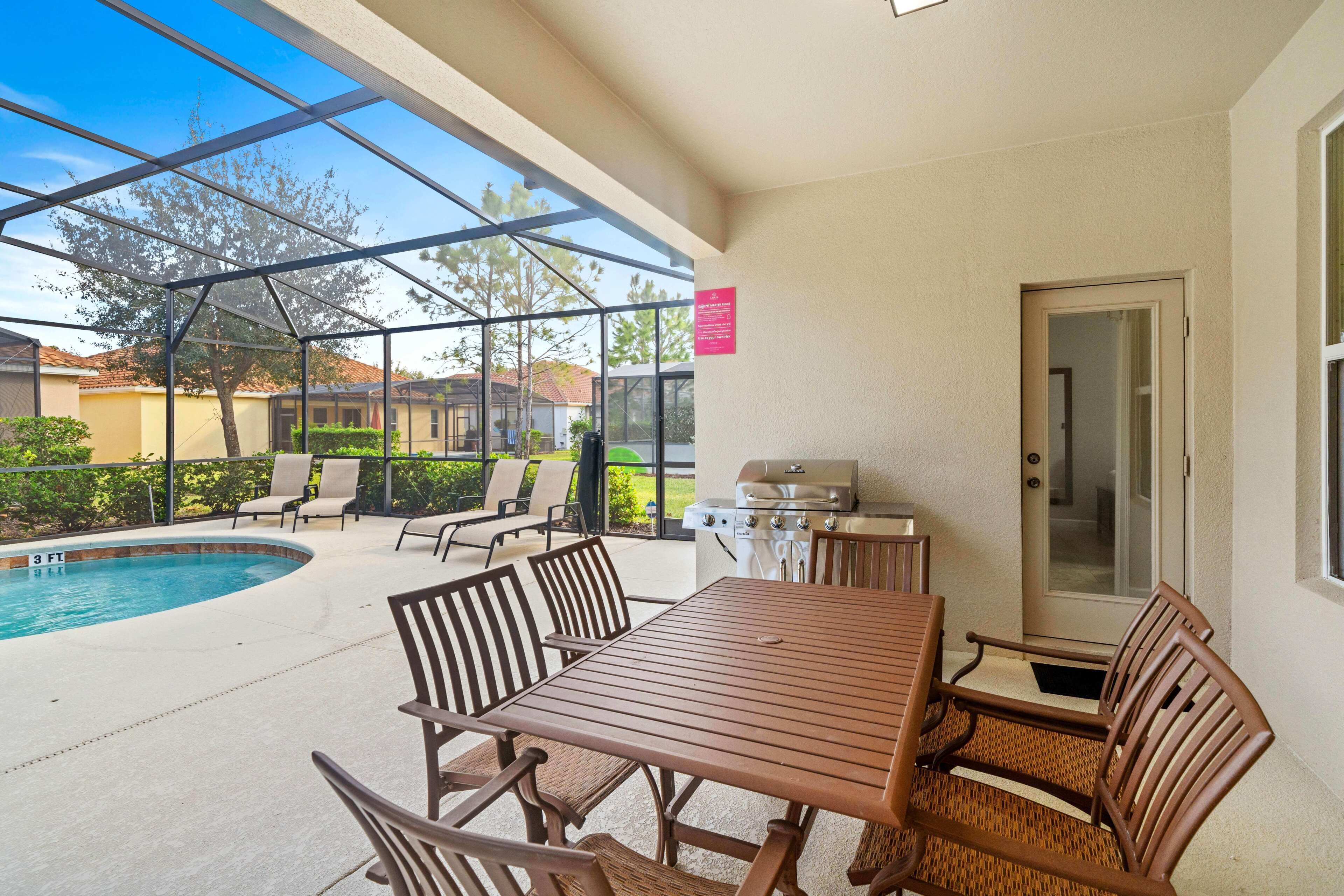 A covered patio with a pool, outdoor seating, and a grill area.