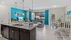 A modern kitchen with a granite countertop, double sink, and dark cabinetry. - 8918 Sydney Avenue (Kissimmee)