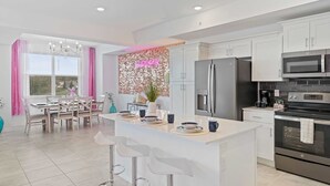 A modern kitchen with white cabinets, stainless steel appliances, and a central island with bar stools. - 3191 Paradox Circle #202 (Kissimmee)