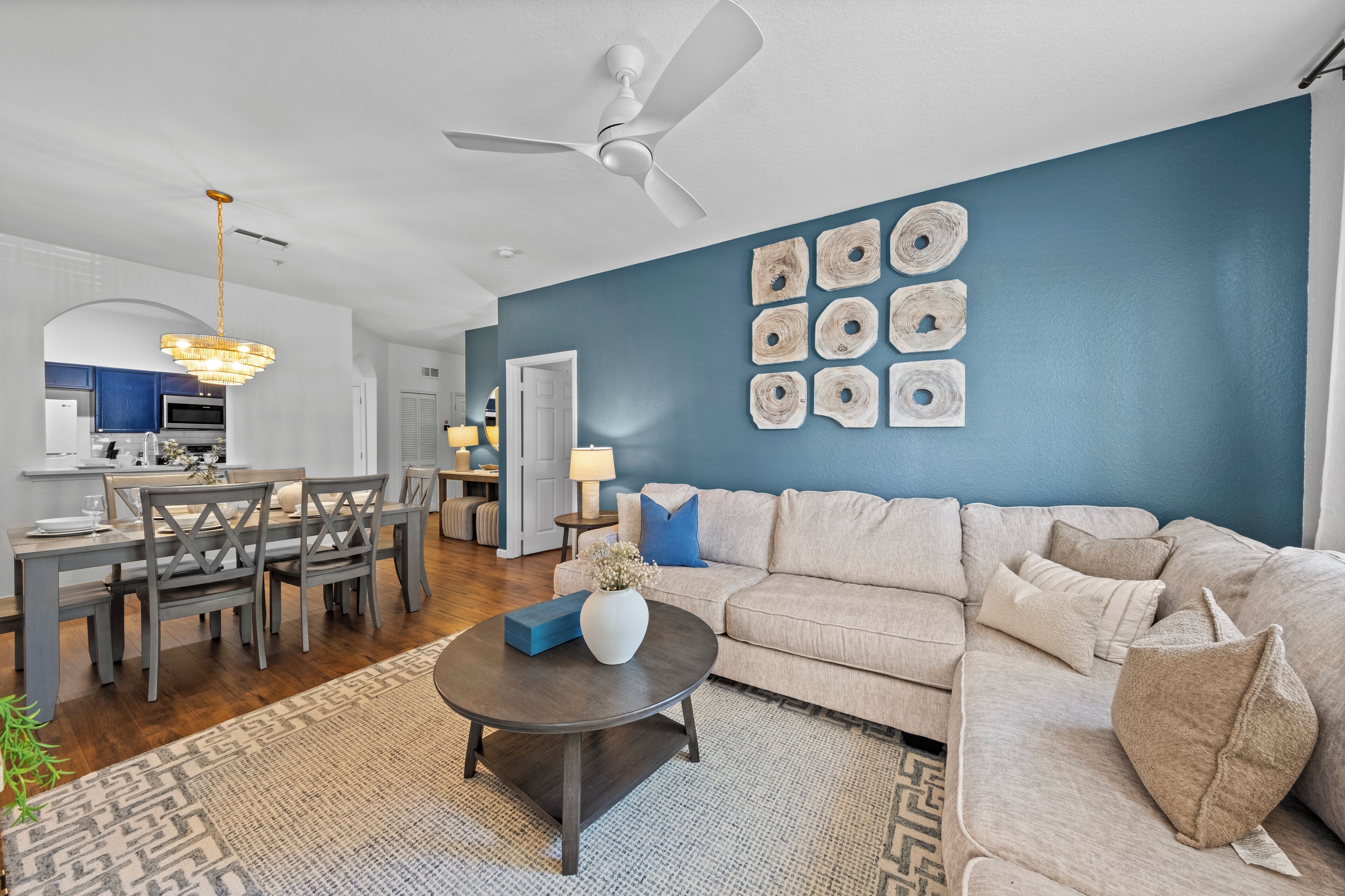 Un salon moderne avec un canapé beige, une table basse foncée et un mur d’accent bleu.