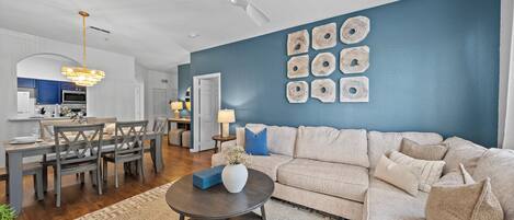 Un salon moderne avec un canapé beige, une table basse foncée et un mur d’accent bleu.
