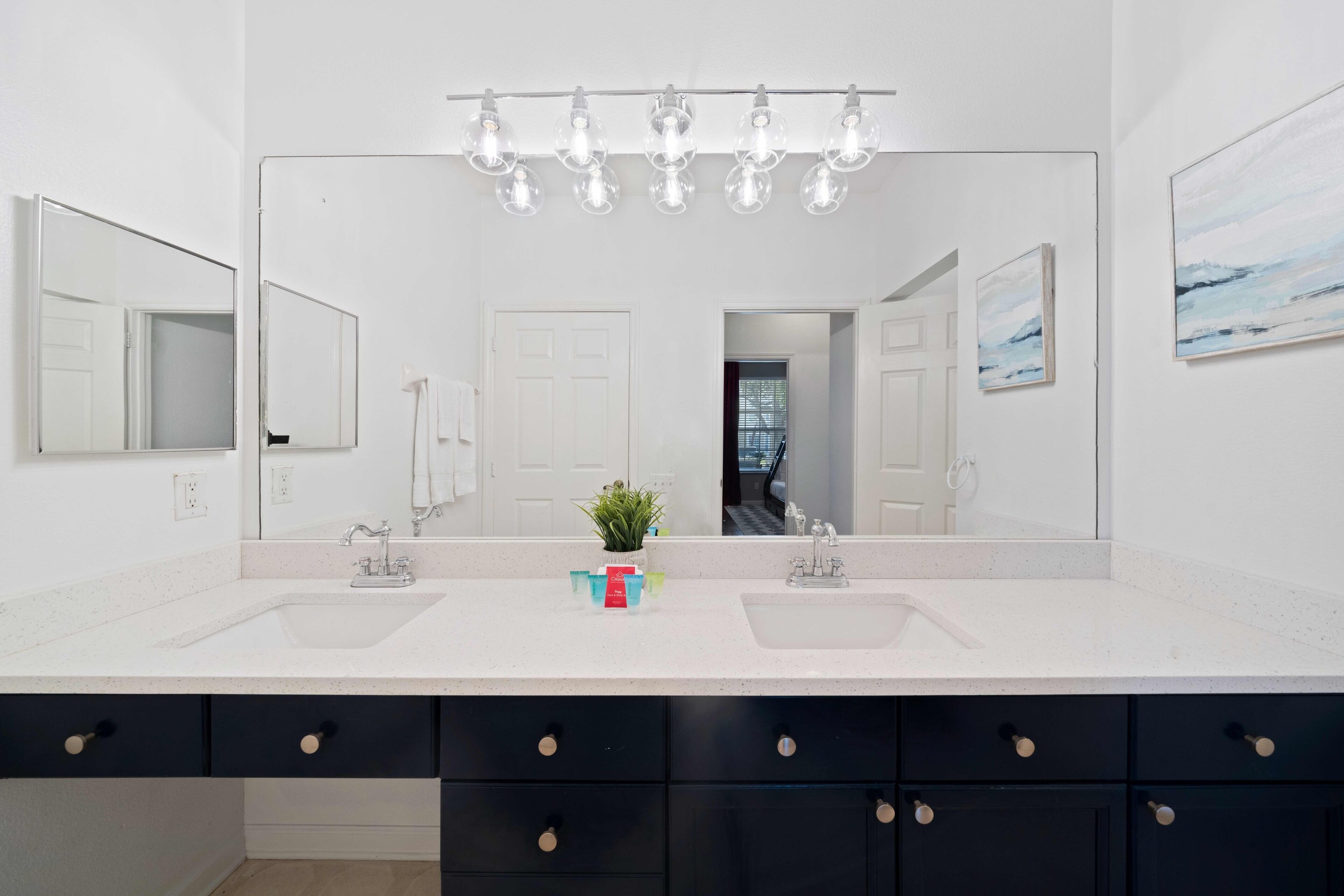 A bathroom with a double sink vanity, a large mirror, and a ceiling light fixture.