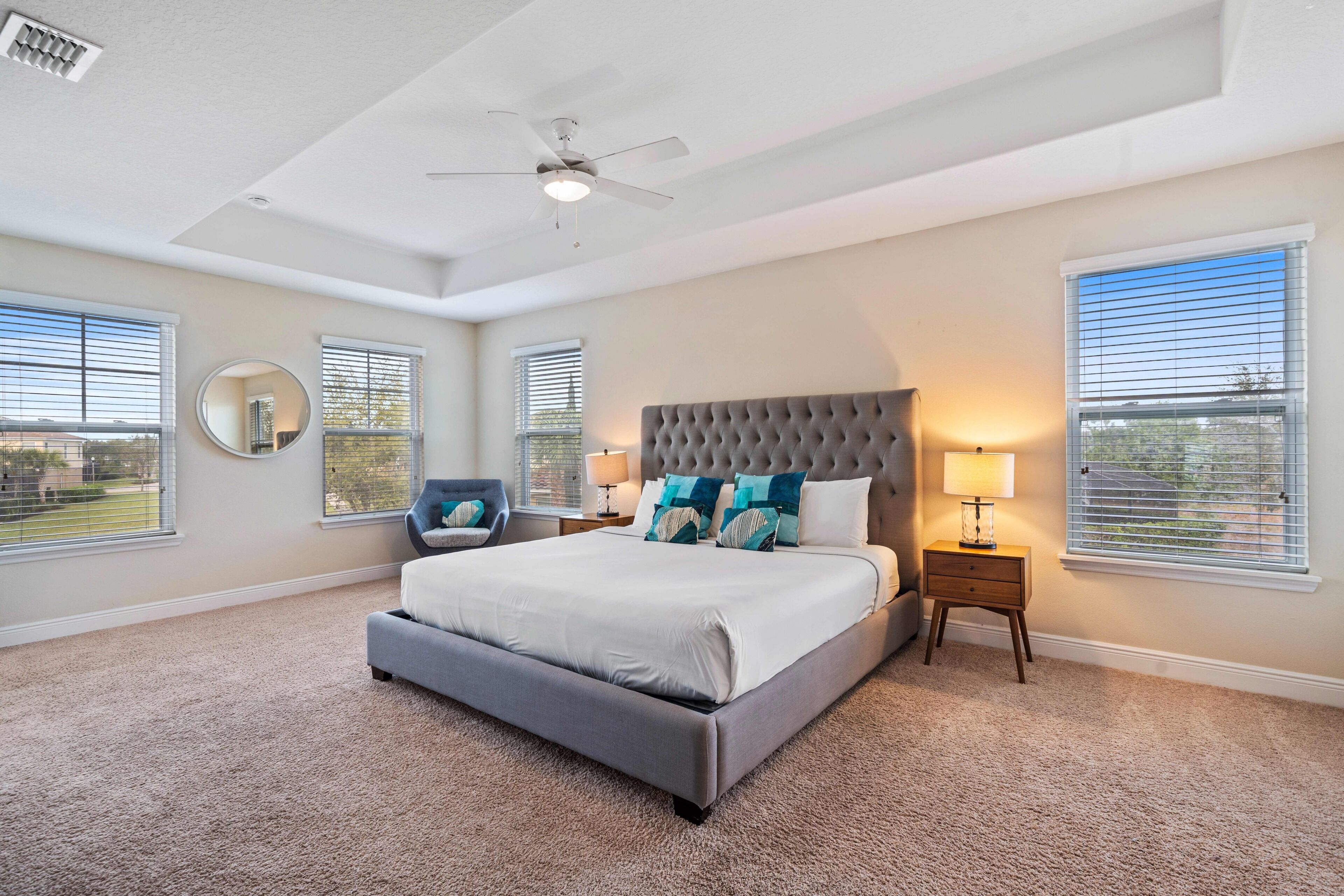 A bedroom with a large bed, a ceiling fan, and two bedside tables with lamps.