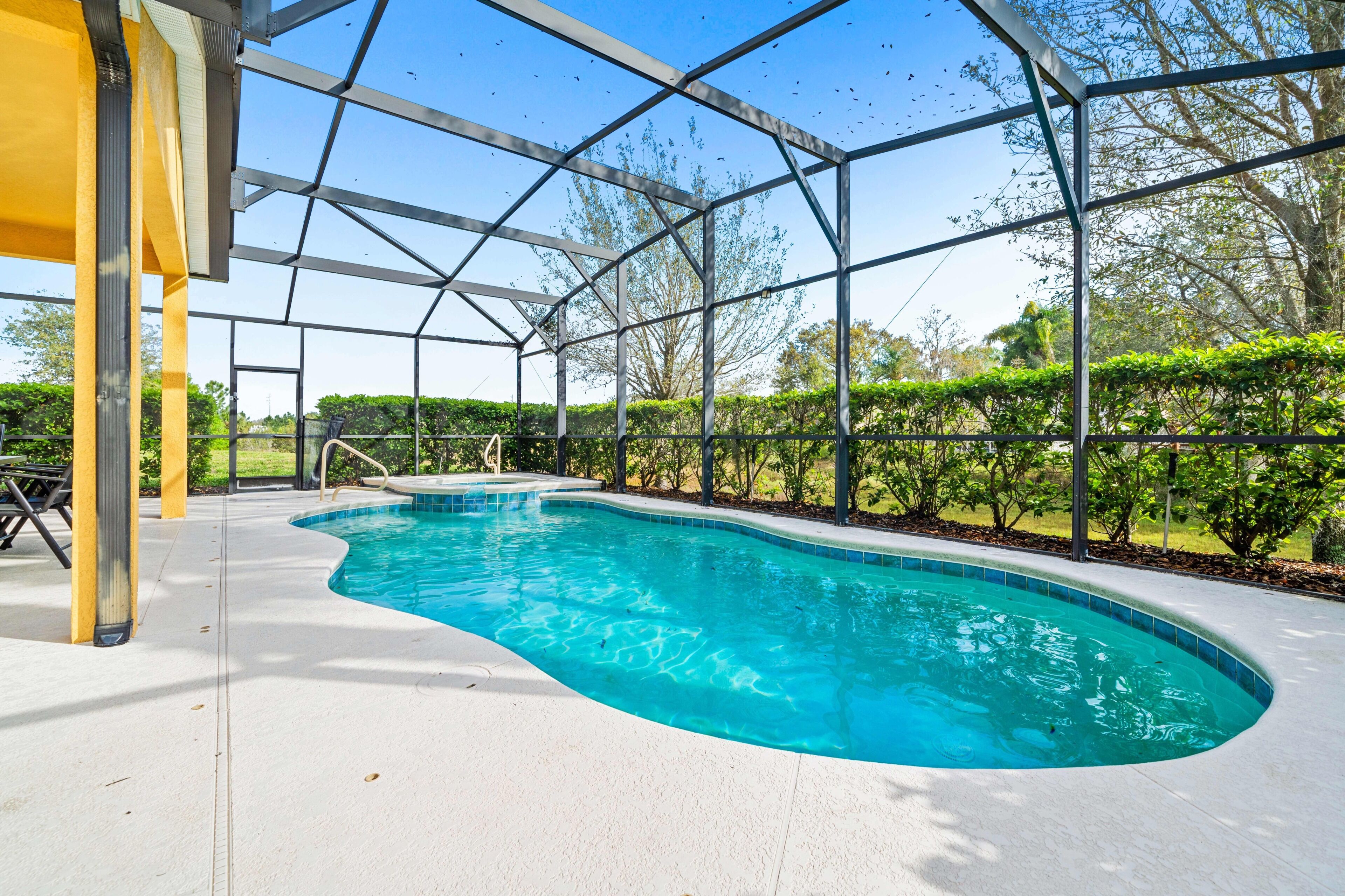 Una piscina con acqua cristallina, circondata da una zona coperta con travi in metallo e pavimento bianco.