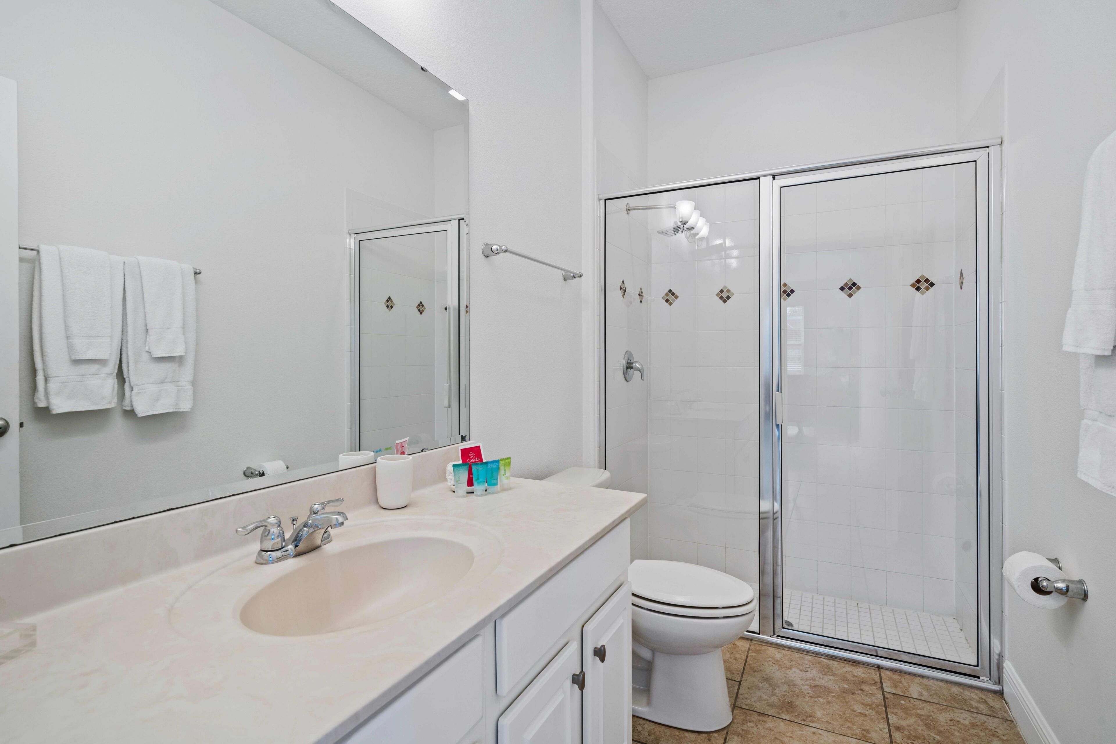 Ein modernes Badezimmer mit großem Spiegel, Waschbecken, Toilette und einer Duschkabine aus Glas.