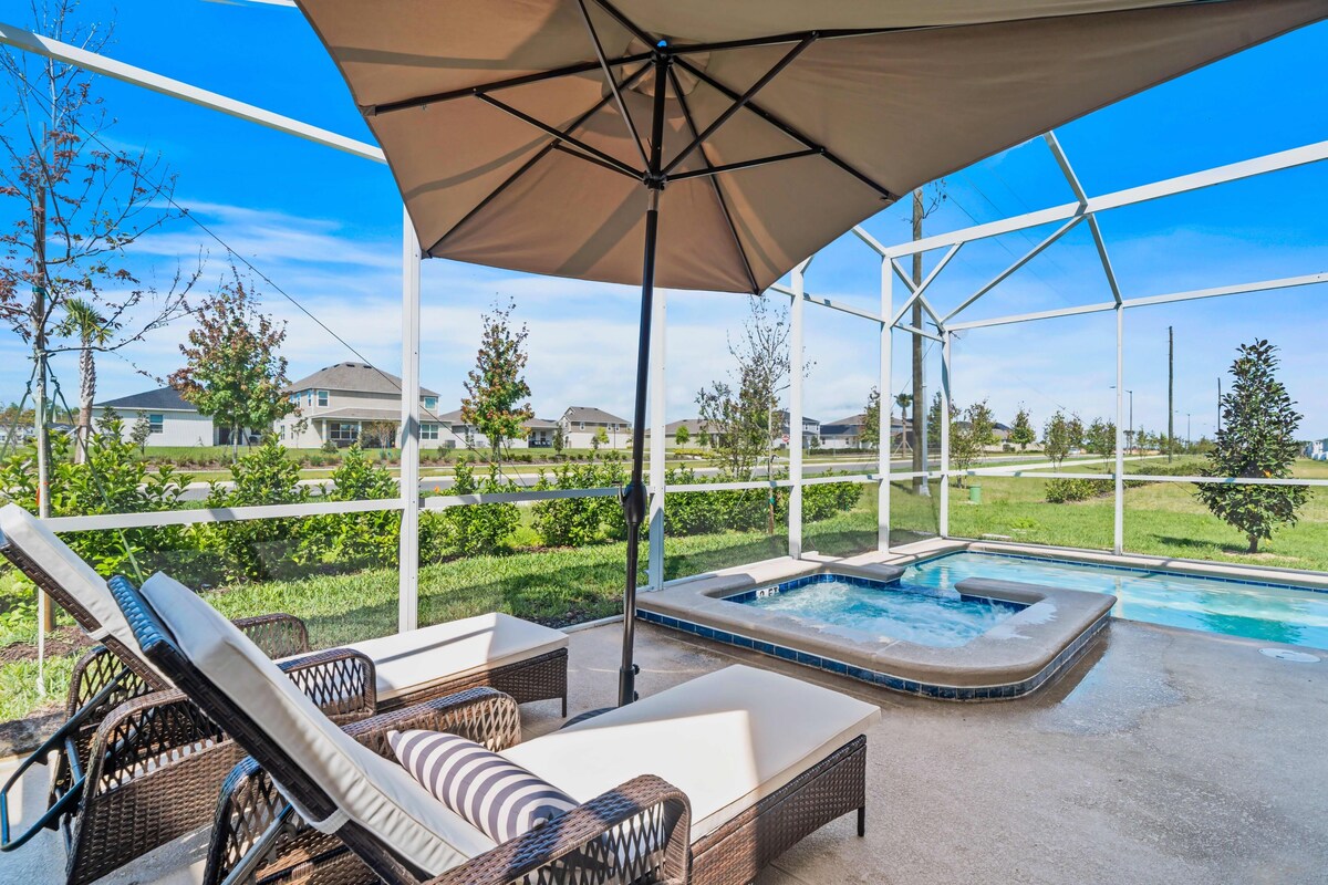 Un patio al aire libre con mobiliario de mimbre, un jacuzzi y vista a un barrio residencial.