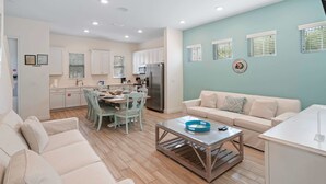 Un salon moderne avec un canapé beige, une table basse et un coin repas comprenant une table et des chaises.