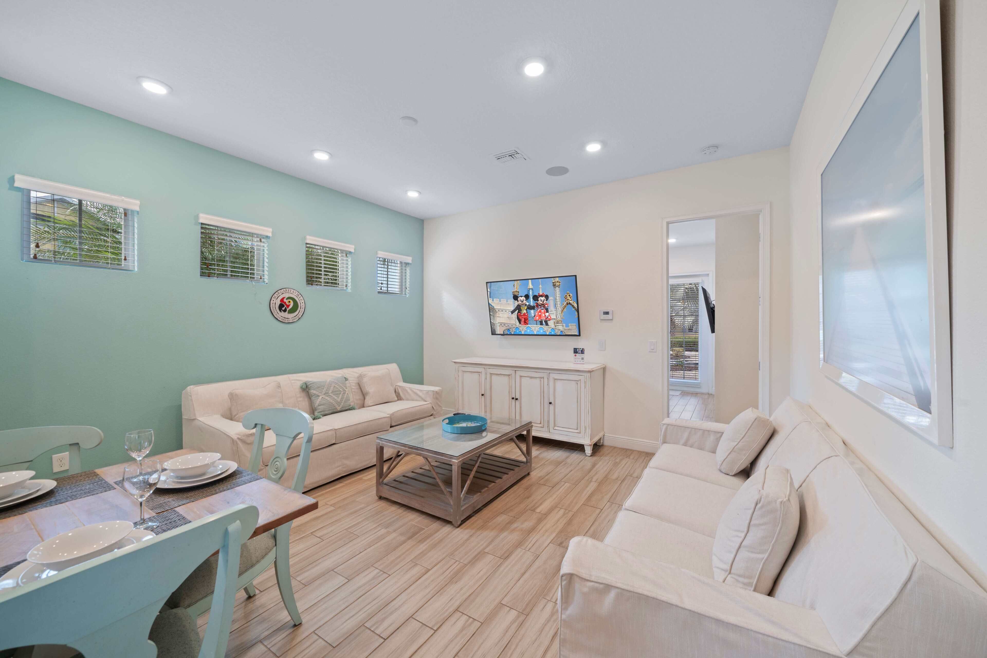 A living room with a dining table set for four, a sofa, a coffee table, and a cabinet.
