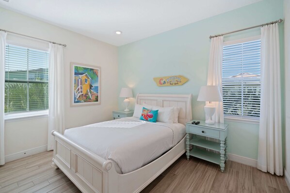 A bedroom with a bed, nightstands, a painting, and a window with blinds.