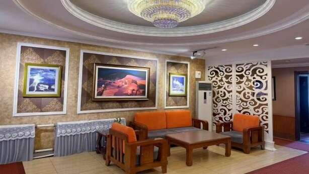 A lobby with a chandelier, framed pictures, a sofa, and a patterned wall. - Hagongda Guest House (Hagongda Metro Station No.2 Branch) (Harbin)