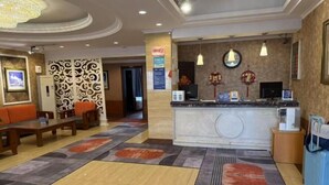 A hotel lobby with a reception desk, seating area, and decorative wall panels. - Hagongda Guest House (Hagongda Metro Station No.2 Branch) (Harbin)
