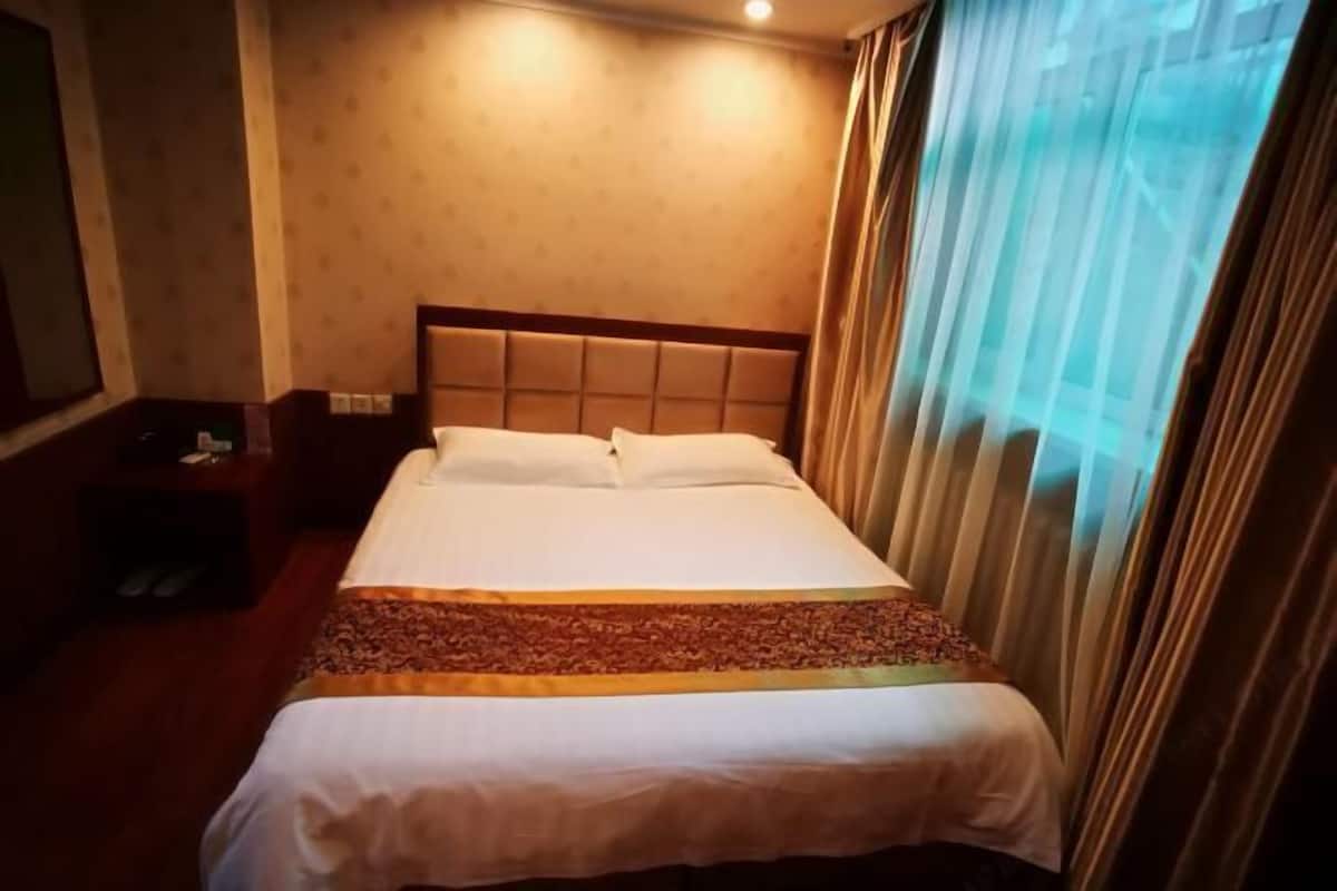A hotel room with a bed, curtains, and a nightstand.