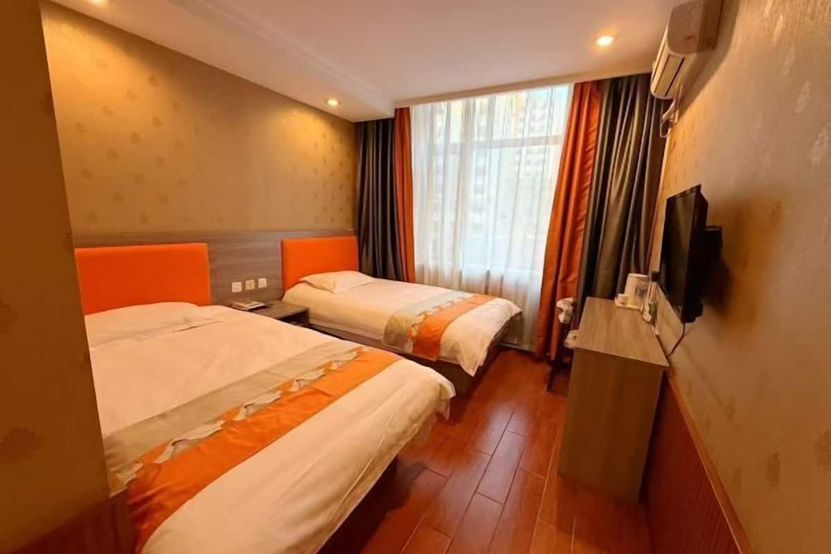 A hotel room with two beds, a TV, and a window with curtains.