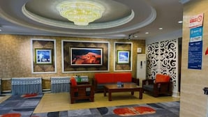 A hotel lobby with a chandelier, framed artwork, a red sofa, and patterned carpets. - Hagongda Guest House (Hagongda Metro Station No.2 Branch) (Harbin)