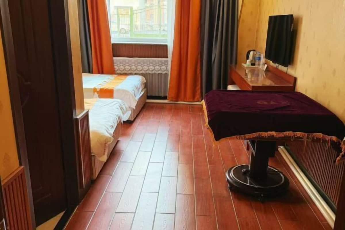 A hotel room with two beds, a desk, a chair, and a window with curtains.