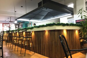 Una zona de bar con mostrador, taburetes y una lámpara colgante.