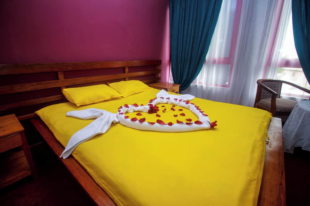 Una cama con una colcha amarilla, un cabecero de madera y una almohada blanca.
