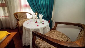 A dining area with a round table, two chairs, a candle, and rose petals. - Big Bang Hotel Antananarivo (Antananarivo)