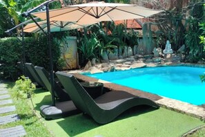 Una piscina amb gandules i un parasol.