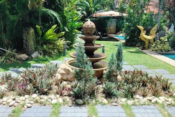 A garden with a tiered water feature, a statue, and various plants. - LePrive Resort (Pattaya)
