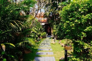 Ein Gartenweg, der zu einem Gebäude im traditionellen Baustil führt.