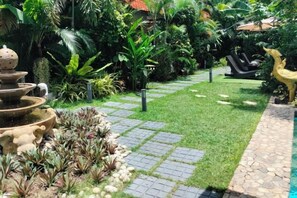 A garden with a stone pathway, a tiered water feature, and various tropical plants. - LePrive Resort (Pattaya)