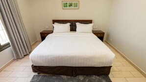 Una camera d'albergo con un letto grande, due comodini, una finestra con tende e un quadro appeso al muro.
