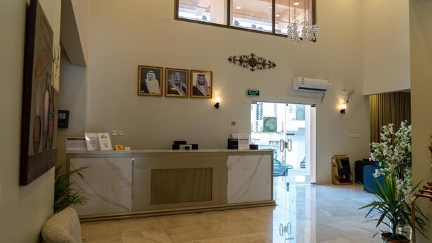 Un'area di accoglienza con un banco in marmo, quadri appesi alle pareti e un lampadario.