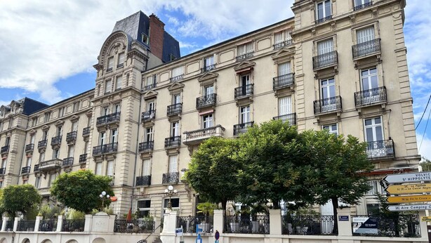 A historic building with multiple balconies, a central staircase, and a clear sky.