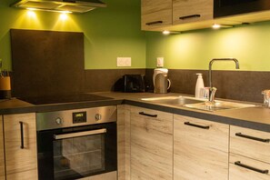A kitchen with a built-in oven, a toaster, a kettle, and a sink with a modern faucet. - Physalis - Studio - 1 bed - 2 people (Châtel-Guyon)