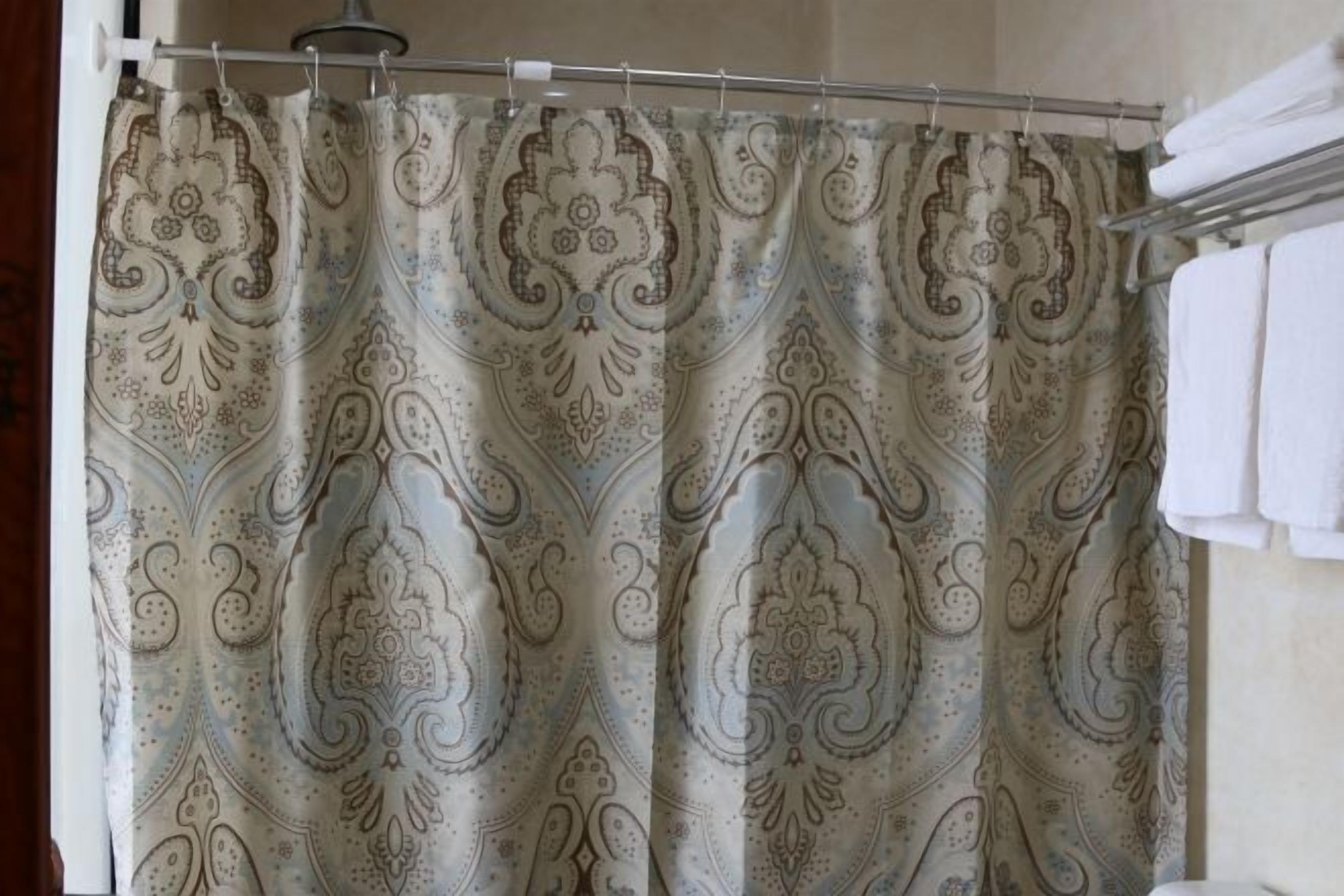 A bathroom with a shower curtain featuring a paisley pattern.