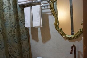 A bathroom with a patterned shower curtain, a mirror with an ornate frame, and a towel rack with folded towels. - ChunHui Inn Hotel (Wuyishan)