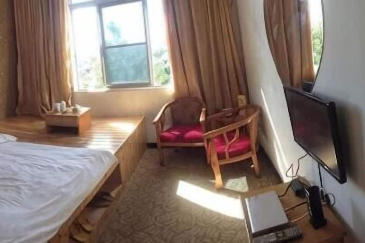 A room with a bed, a desk, a chair, and a television.