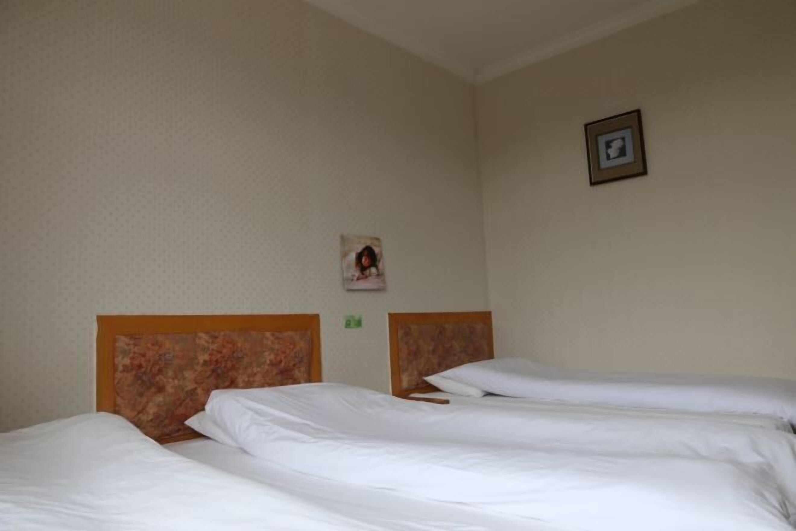 Ein Hotelzimmer mit zwei Betten, einem gerahmten Bild an der Wand und einem kleinen grünen Schild.