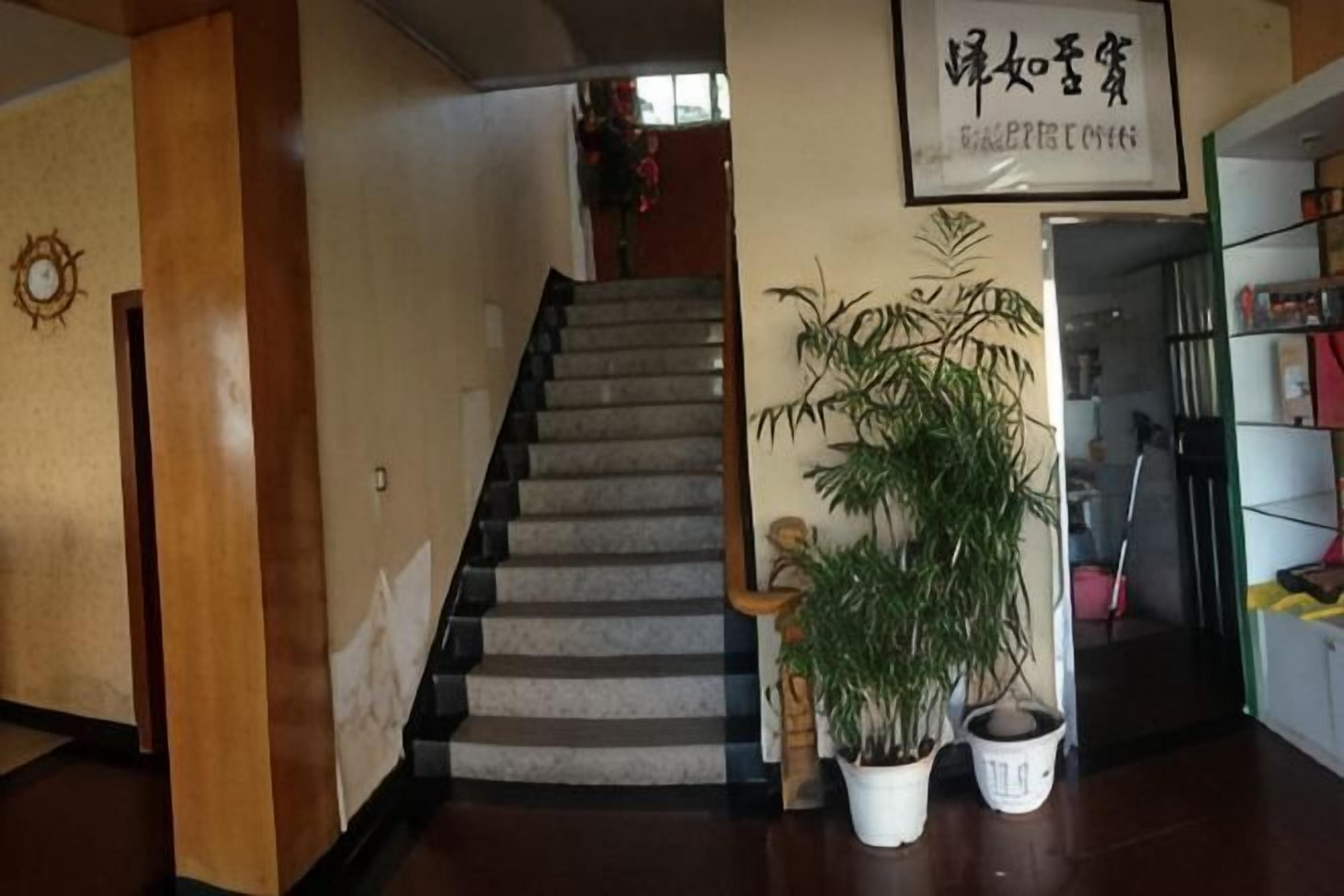A staircase with a potted plant, a framed sign, and a bookshelf.