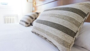 Un lit bien fait, avec des oreillers à rayures et une couette blanche.