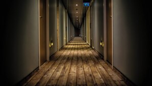 Un long couloir étroit, doté d’un plancher en bois et de murs de part et d’autre.
