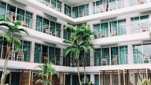 Un hôtel à plusieurs étages doté de balcons, de palmiers et d’une architecture moderne.