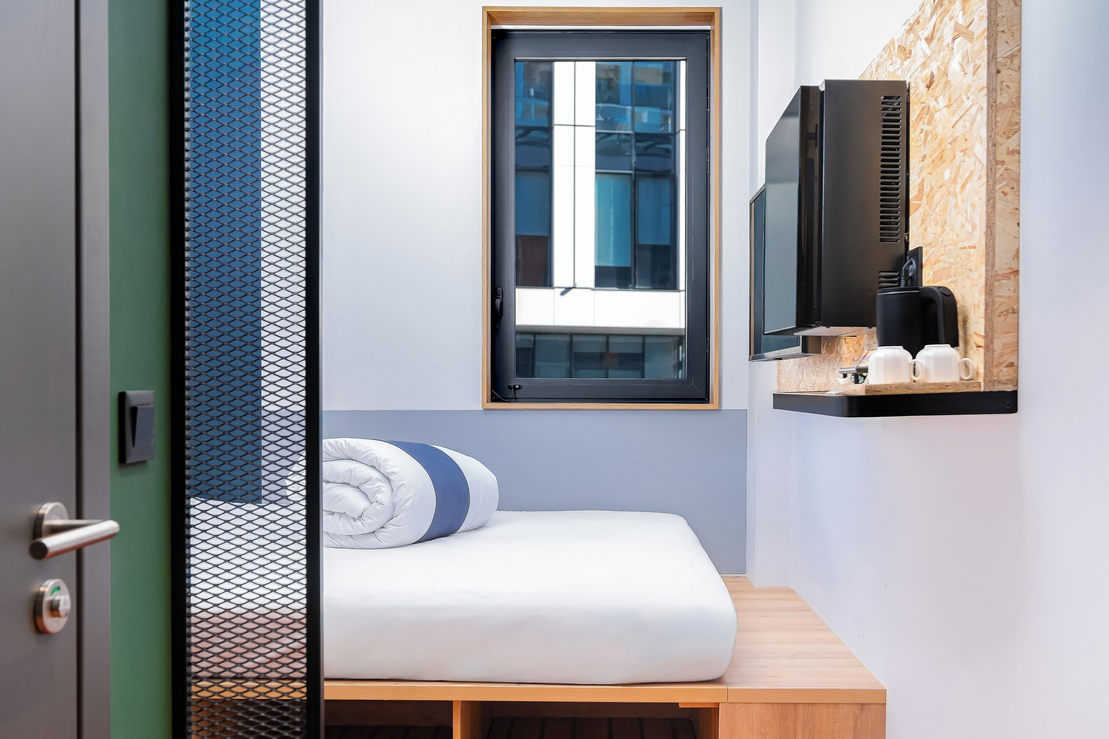 A modern bedroom with a bed, a window, and a mounted television.