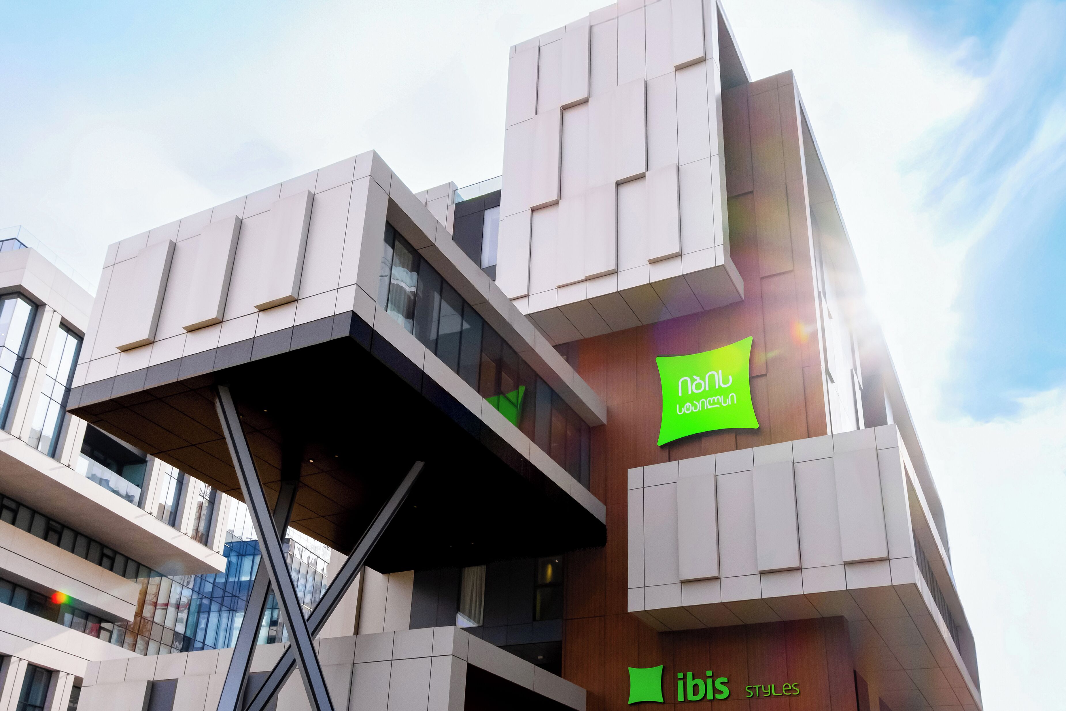 Un edificio moderno con un diseño arquitectónico único, que presenta un cartel verde llamativo con letras blancas.