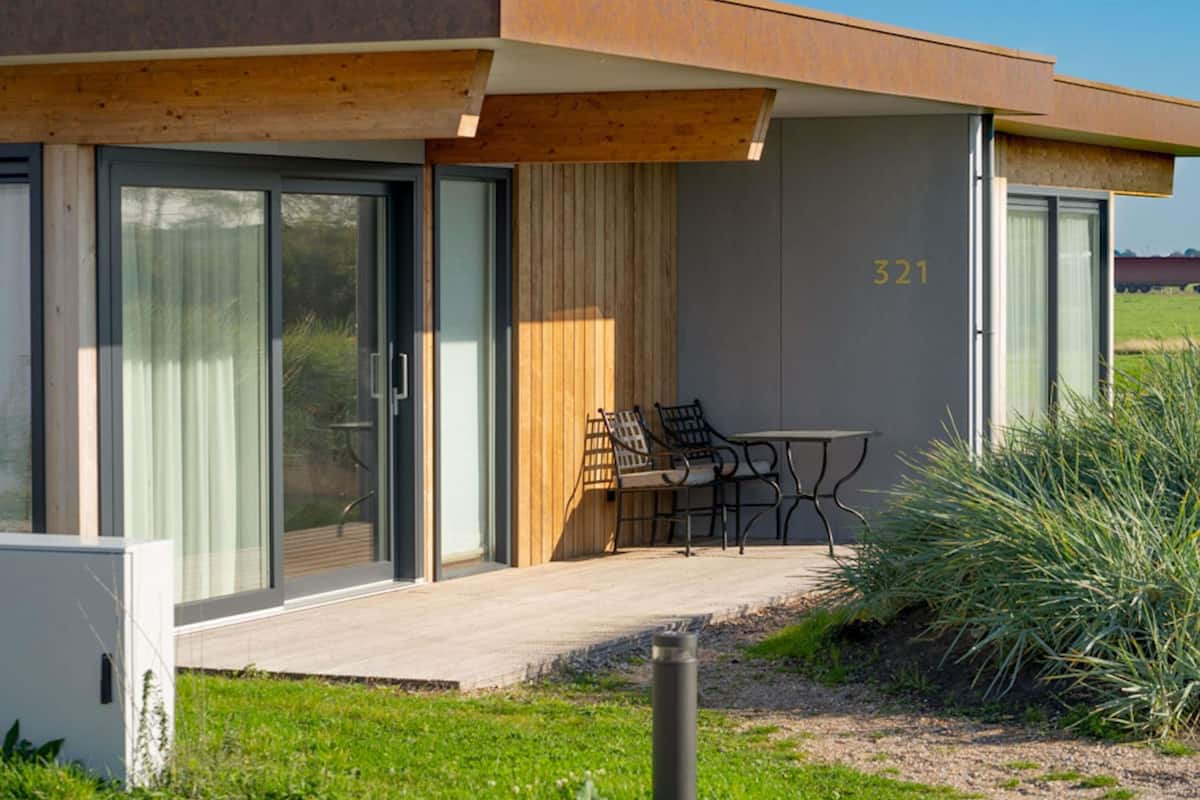A modern building with a covered patio, a number '321' on the wall, and outdoor seating.
