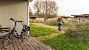 A person riding a bicycle on a path next to a building with a number 312 sign. - Hotel Ter Zand - Handwritten Collection (Burgh-Haamstede)