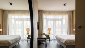 A hotel room with two beds, a dining table, chairs, lamps, and a TV. - Hotel Ter Zand - Handwritten Collection (Burgh-Haamstede)