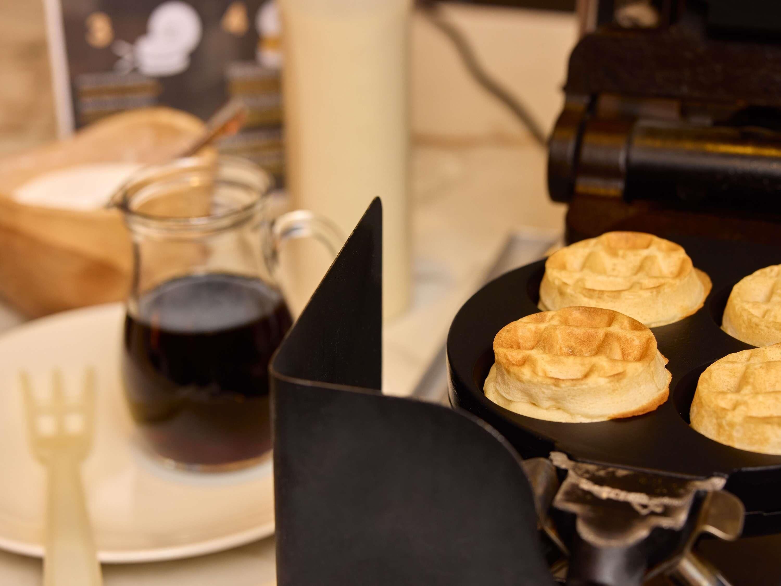 A breakfast setting with waffles, a coffee pot, and a plate.