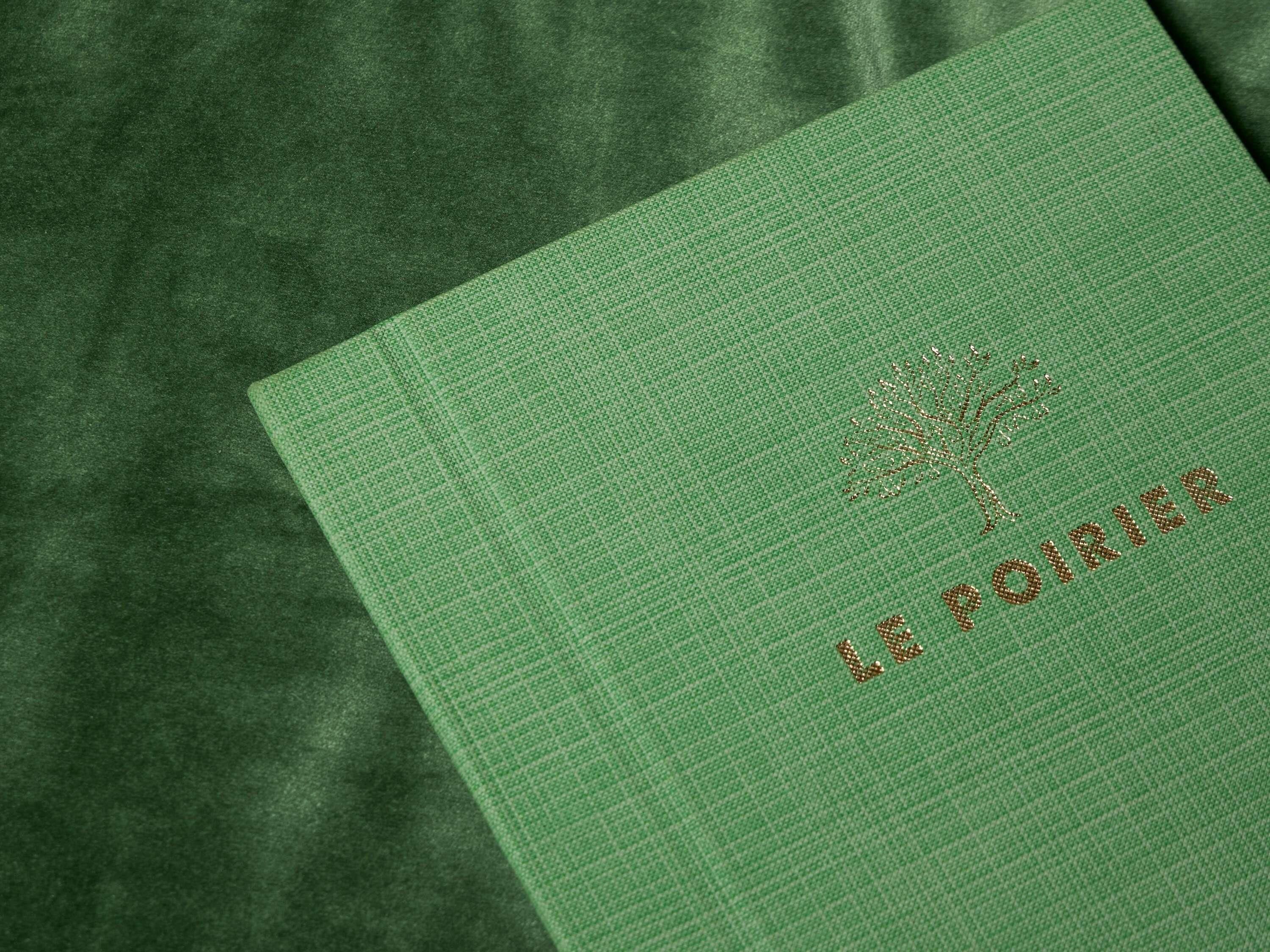 Un livre vert dont le titre est imprimé en lettres dorées en relief et dont la couverture est ornée d’un motif représentant un arbre.