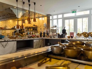 A kitchen with marble countertops, copper cookware, and a view of the outdoors through large windows. - Hotel Ter Zand - Handwritten Collection (Burgh-Haamstede)