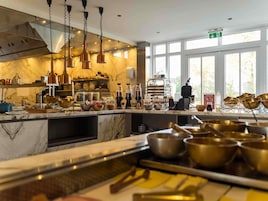 Una cocina con encimeras de mármol, utensilios de cocina de cobre y vistas al exterior a través de amplios ventanales.