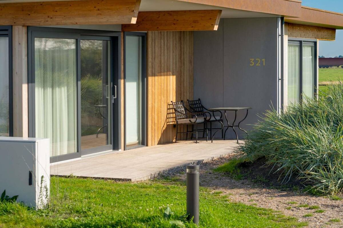 A modern building with a large sliding glass door, a wooden deck, and a number '321' on the wall.